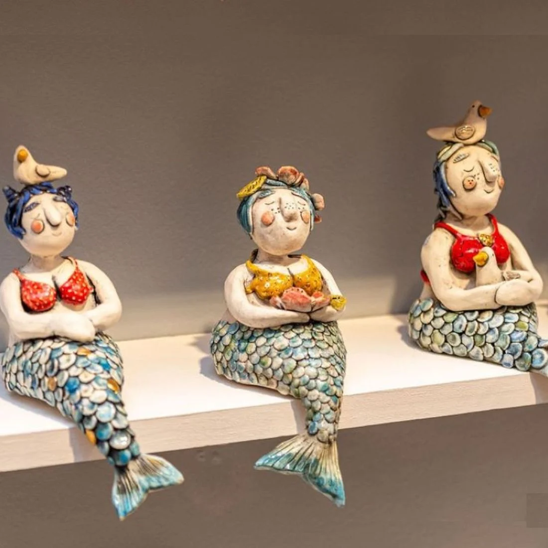 3 mermaid statues sitting on a shelf